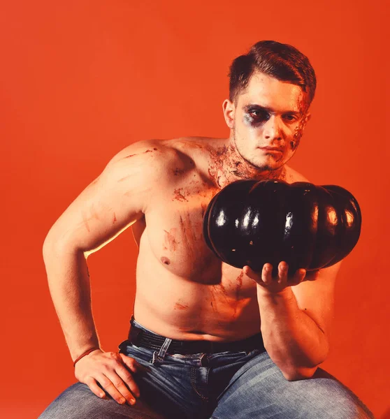 Man with scary face and sexy torso on orange background.