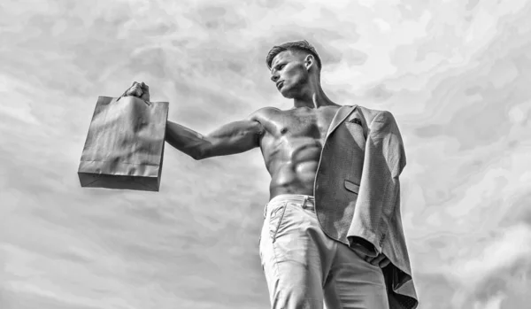 Atraktivní macho chlap nést nákupní tašku z balicího papíru. Prodejní sezóna. Muž svalnatý sportovec drží pozadí oblohy nákupní tašku. Žhavé výprodeje a slevy. Vezměte tento balíček. Zdravé produkty Eco — Stock fotografie