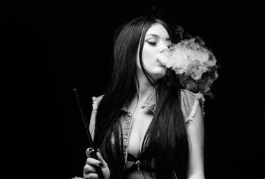 Nargileyle rahatlıyorum. Nikotin bağımlılığı. Çekici göğüslü esmer sigara içme cihazı. Kız buharı. Nargile barı. Elektronik sigara. Beyaz duman bulutu. Vapur kullanmak seksidir. Moda kızı buharlaşması