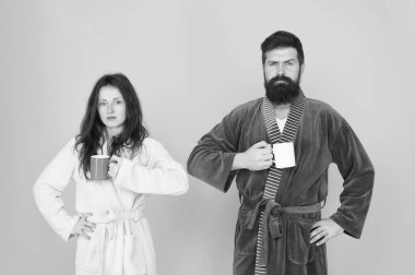 Her sabah kahveyle başlar. Bornozlu ve kupalı bir çift. Kahvaltı konsepti. Sakallı ve uykulu kadın ile adam sabah kahve veya çay tadını çıkarın. Banyo kıyafetli adam çay kahvesi tutuyor. Yeni güne başlayın