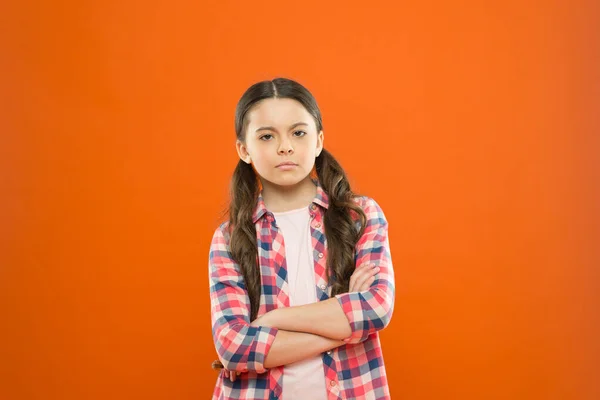 O que devo fazer? Dia das crianças. memória da infância. menina laranja fundo. moda infantil. menina da escola séria. uniforme de trabalhador. Cabelo comprido. menina pequena camisa xadrez. criança triste — Fotografia de Stock