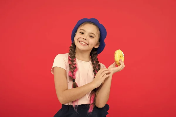 Loja de doces e conceito de padaria. Crianças enormes fãs de rosquinhas assadas. Impossível resistir ao donut feito de fresco. Menina segurar vidros bonito donut na mão fundo vermelho. Garota sorrindo menina pronta para comer donut — Fotografia de Stock