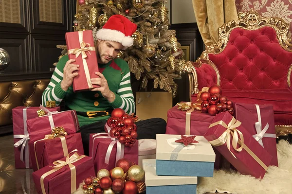 Χριστούγεννα δεν είναι πλήρης χωρίς δώρα. Ευτυχισμένος άνθρωπος με κουτιά δώρων Χριστουγέννων. Ο άνθρωπος με το καπέλο santa κρατήστε χριστουγεννιάτικα δώρα. Τύπος γιορτάζει Χριστούγεννα στο σπίτι. Χριστουγεννιάτικα δώρα παράδοση — Φωτογραφία Αρχείου