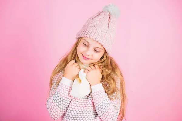 Ребенок улыбается носить вязаный аксессуар. Девочка носит симпатичную вязаную модную шляпу и шарф аксессуар. Зимний модный аксессуар. Концепция зимнего аксессуара. Девушка длинные волосы мечтательный настроение розовый фон — стоковое фото