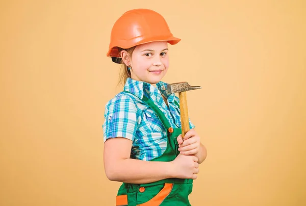Küçük bir kız atölyede çekiçle tamir ediyor. Kendini geliştirmek için aletler. Tamir et. Çocuk bakımı. Geleceğin mesleği. İnşaat mühendisi mimar. Şapkalı çocuk işçi. Tamirhanede çalışıyorum. — Stok fotoğraf