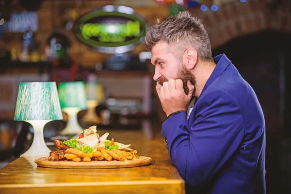 Enjoy meal. High calorie snack. Cheat meal concept. Hipster hungry eat pub fried food. Manager formal suit sit at bar counter. Delicious meal. Man received meal with fried potato fish sticks meat