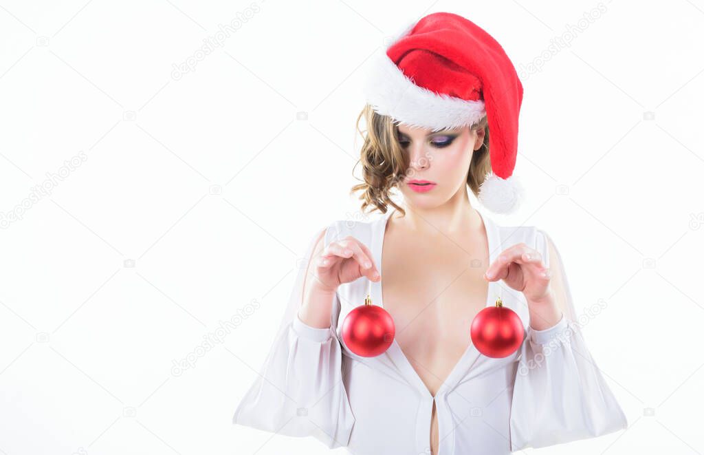Christmas balls symbol implant female breasts. Christmas miracle concept. Breasts augmentation as gift for new year. Plastic surgery. Girl santa hat hold balls decorative ornament in front of breasts