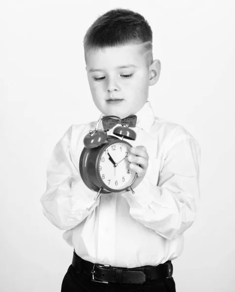 Esmoquin. Feliz infancia. Hora de la fiesta. Empresario. Ropa formal. Gestión del tiempo. Buenos días. niño pequeño con despertador. Es hora de relajarse. niño feliz con reloj retro en corbata de lazo. ¿Qué hora es —  Fotos de Stock