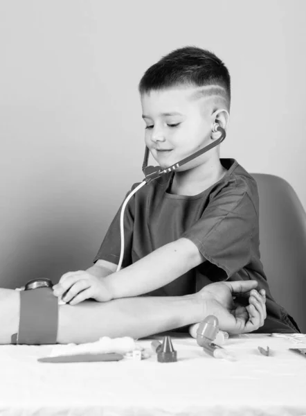 의료. 아이 작은 의사는 청진기와 의료 도구와 함께 테이블을 앉아있다. 의학 개념. 혈압 측정. 건강 검진. 의학 교육. 소년 귀여운 아이 미래 의사 경력 — 스톡 사진