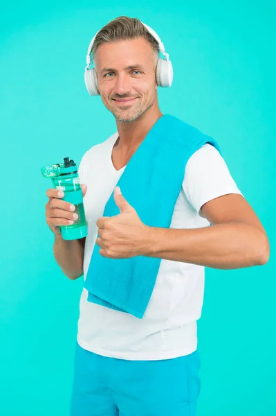 Donner comme à la santé. Beau geste d'homme les pouces vers le haut sur fond bleu. Sportsman dans les écouteurs promouvoir l'activité de santé. Exercice physique avantages santé. Augmentez votre niveau d'eau et votre santé — Photo