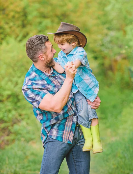 small boy child help father in farming. father and son in cowboy hat on ranch. kid in rubber boots. happy man dad in forest. human and nature. family day. happy earth day. Eco farm. family time