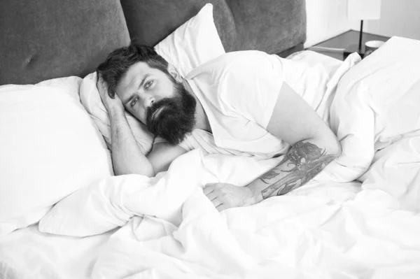 Un hipster barbuto che ha problemi a dormire. Il ragazzo sdraiato a letto cerca di rilassarsi e addormentarsi. Tecniche di rilassamento. Violazioni del sonno e della veglia. Ho bisogno di riposo. Disturbi del sonno concetto — Foto Stock