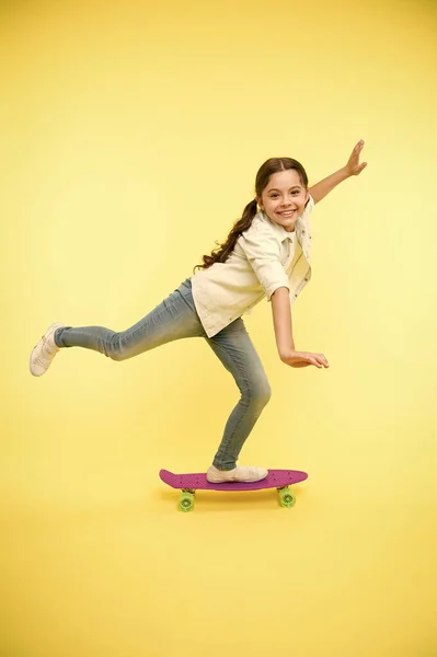 El chico se divierte con Penny Board. Hobby actividad favorita. Cara sonriente infantil en monopatín. Penny board lindo monopatín colorido para niñas. Vamos a montar. Chica paseo penny board fondo amarillo — Foto de Stock