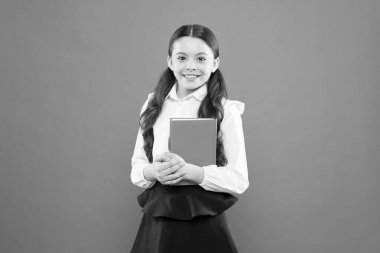 Okula geri dön. mutlu çocuk. okuma dersi. Kitap mağazası konsepti. Okul üniformalı küçük bir kız. turuncu arka plan üzerine notlar yazma kız öğrenci. bilgi formu kitap almak. Eğitim ve öğretim. Eğitim