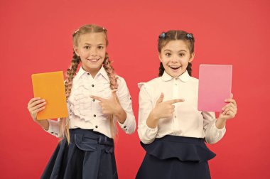 Kitaplara tutkuyla bağlı. Mutlu küçük kızlar kırmızı arka plan la ilgili kitapları işaret ediyor. Sevimli küçük çocuklar ansiklopedi veya el kitapları ile gülümseyen. Öğrenciler ve öğrenciler için eğitim kitapları