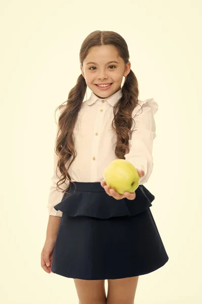 Дівчина мила зіниця тримає яблучні фрукти стояти на білому тлі. Хлопчик щасливий тримай яблуко. Концепція шкільних закусок. Здорове харчування. Яблучний вітамінний перекус. Дитяча школярка носить формальну форму тримає яблуко — стокове фото