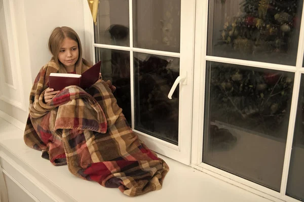 节日快乐。小孩在圣诞前夜看书。小女孩喜欢读圣诞故事。用格子包裹的小读者坐在窗台上。儿童画册。神奇的圣诞精神 — 图库照片