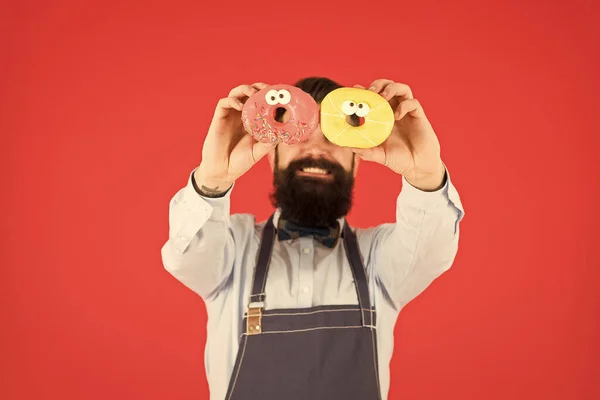 Випічка - це мистецтво. Свіжі пончики вибірковий фокус після випічки в руках бородатого чоловіка. Глазуровані пончики за рецептом випічки. Випічка найкращий десерт — стокове фото