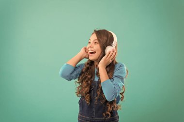 Kulaklıklarımla müzik daha iyi geliyor. Mavi arka planda kulaklık takan küçük bir kız. Kulak stereo kulaklıkmüzik dinlesevimli çocuk. Modern kulaklık takan sevimli küçük çocuk