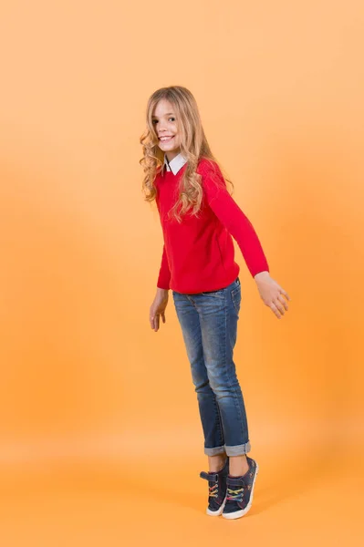 Ragazza in maglione rosso e jeans stand in punta di piedi — Foto Stock