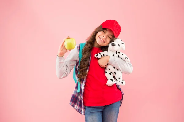 Їж органічно. Щаслива маленька дитина тримає іграшку та органічні яблучні фрукти на рожевому фоні. Здорова маленька дівчинка вибирає натуральну органічну їжу. Діти здоров'я і майбутнє. Перейти органічно — стокове фото