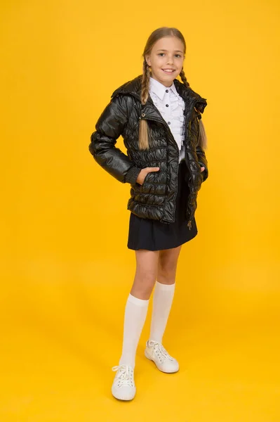 Concept de mode. Achetez des vêtements pour la saison scolaire. Tenue de mode écolière. Des vêtements chauds. Automne automne hiver. Charmant petit enfant. Boutique de mode. Jolie fille porter une veste noire sur fond jaune — Photo