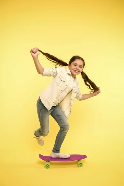 Hobby Lieblingsbeschäftigung. Kinderlächelnde Gesichter stehen auf dem Skateboard. Penny Board niedlich buntes Skateboard für Mädchen. Lasst uns fahren. Mädchen fahren Penny Board gelbem Hintergrund. Kind hat Spaß mit Penny Board — Stockfoto