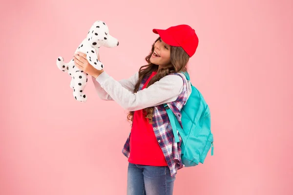 Игры для детей. Счастливый маленький ребенок играет с мягкой собакой на розовом фоне. Маленький ребенок держит игрушку. Детская игра — стоковое фото