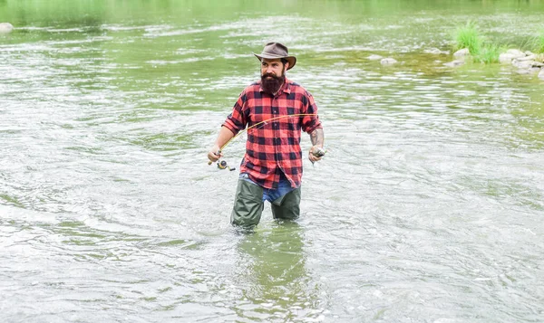 Man bearded fisher. Fishing requires to be mindful and fully present in moment. Fisher fishing equipment. Rest and recreation. Fisher masculine hobby. Fish on hook. Brutal man stand in river water — Stock Photo, Image