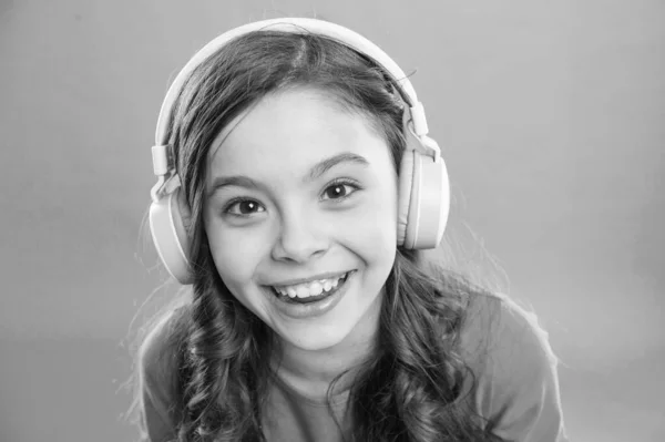 Happy songs to make you smile. Happy small girl listening to music on blue background. Little child enjoying song playing in headphones with smile on happy face. Happy fun and upbeat