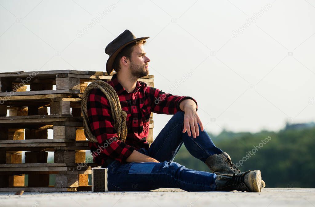Farmer enjoy view from his farm. Romanticism of western culture. Farmer in hat sit relax. Peaceful mood. Watching sunset. Farmer cowboy handsome man relaxing after hard working day at ranch