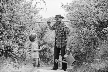 Ağaç dikme geleneği. Bahçedeki küçük yardımcı. Çiçek ekiyorum. Bitki yetiştiriyorum. Çocuk ve babası doğada sulama tenekesi ve kürekle. Baba oğluna bitkileri yetiştirmeyi öğretiyor. Ağaç dikme günü. Ağaç dikiyorum.