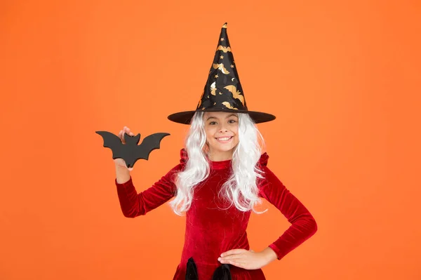 バットは私の友人です。魔女の衣装を着た小さな子供。ハロウィンパーティーだ。黒い魔女の帽子の少女。秋休み。お祝いに参加。魔法の呪文だ。白い髪の小さな魔女。ウィザードまたは魔術師 — ストック写真