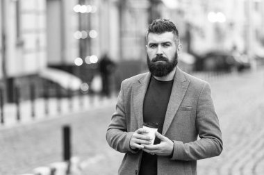 Gevşeme söz konusu. Adam hipster içki kahve kağıt bardak sakallı. İyi bakımlı işadamı kahve arası açık havada kentsel arka plan tadını çıkarın. Düşünceli ama rahat. Yürümek ve taze sıcak kahve keyfini çıkarın