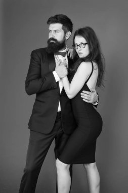 Smokinli ve zarif kız lı bir çift. Erkek sakallı hipster ve resmi elbise kırmızı arka plan lı kadın. Resmi moda ve zarif giysiler. Lüks moda butiği. Moda giyim mağazası. Resmi etkinlik