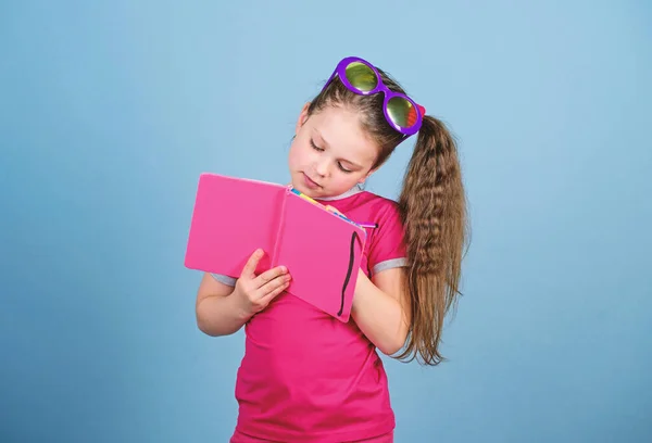 Libro de lectura. Moda de verano. pequeña chica feliz en gafas con cuaderno. notas del diario. Pequeña chica de belleza escribir sus recuerdos. hacer planes para vacaciones de verano y vacaciones. colegiala listo para la lección — Foto de Stock