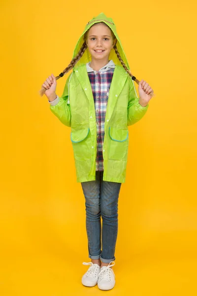 Vodotěsný plášť. Vodotěsná látka pro vaše pohodlí. Školačka v plášti s kapucí si užívá deštivého počasí. Deštivzdorné příslušenství. Vodotěsné oblečení by si mělo vyzkoušet každé dítě. Děvče šťastné nosit pláštěnku — Stock fotografie