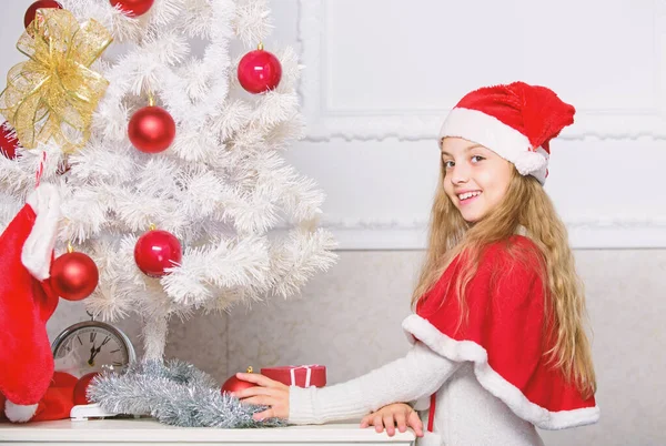 Child decorating christmas tree with red balls ornaments. Girl kid decorating christmas tree. Cherished holiday activity. Kid in santa hat decorating christmas tree. Family tradition concept — Stock Photo, Image