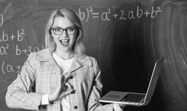 Online skolgång koncept. Kvinna bära glasögon innehar laptop surfa Internet. Stor resurs för lärarna. Utbildare Smart Clever Lady med modern laptop söka information svarta tavlan bakgrund — Stockfoto
