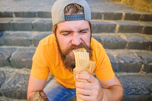 A melhor comida da cidade. Um homem barbudo a comer comida insalubre. Um tipo esfomeado que gosta de comida de rua. Hipster lanche com fast food durante a pausa para refeições nas escadas — Fotografia de Stock