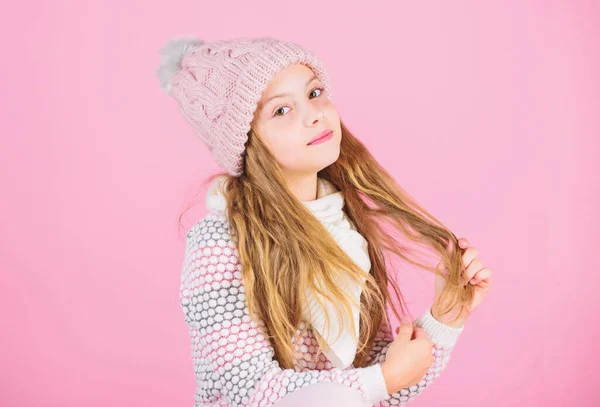 Tips for caring for knitted garments. Child long hair warm soft woolen hat enjoy softness. Kid girl wear knitted soft hat pink background. Keep knitwear soft after washing. Soft knitted accessory