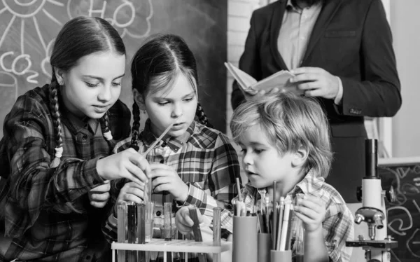 Inspirerade att jobba hårt. Happy barn lärare. gör experiment med vätskor i kemilabbet. kemilabbet. tillbaka till skolan. barn i Lab Coat lärande kemi i skolan laboratorium — Stockfoto