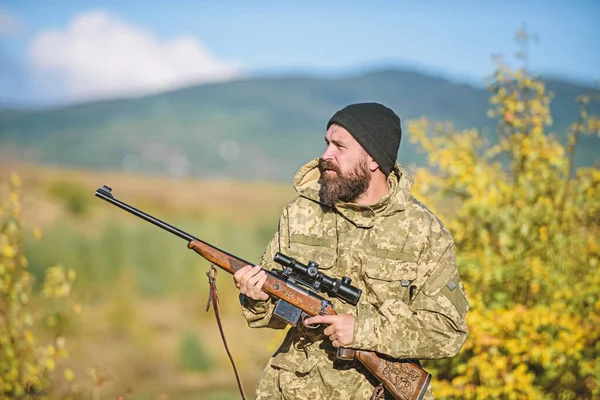 Bearded hunter spend leisure hunting. Focus and concentration of experienced hunter. Hunting and trapping seasons. Hunting masculine hobby. Man brutal gamekeeper nature background. Hunter hold rifle