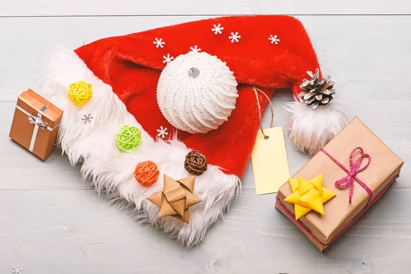 圣诞老人送的圣诞礼物圣诞老人帽子白色背景顶视图。气氛就是细节。寒假属性。新年和圣诞装饰品。圣诞老人帽子和圣诞礼品盒 — 图库照片