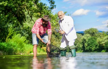 Aile bağı kurma zamanı. İş adamının uçan balık hobisi. emeklilik balıkçılığı. Emekli baba ve olgun sakallı oğul. İki erkek arkadaş birlikte balık tutuyor. Mutlu balıkçı arkadaşlığı. Yakalama ve balıkçılık konsepti