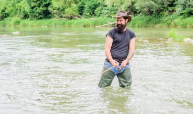 Balıkçı ekipmanlarıyla. Balıkçılık erkek hobisi. Zalim bir adam nehir suyunda lastik bot giyer. Balık tutmak eğlencelidir. Fisher hafta sonu aktivitesi. Balık oltaya geldi. Vahşi doğada eğlence.