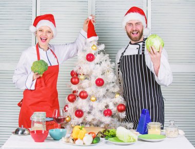Çift sağlıklı vejetaryen yemek birlikte Noel yemeği için hazırlanıyor. Christmas yemek yemek. Erkek ve kadın şef santa şapka Noel ağacı yakınındaki. Gizli madde aşktır. Noel tarifi kavramı
