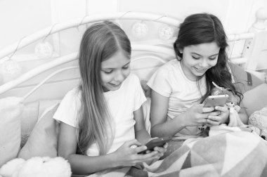 Sadece ekranda parmağı kaydırıyorum. Cep telefonu ile mutlu küçük çocuklar. Telefonla Noel ve Yeni Yıl tebrik mesajlaşma. Küçük kızlar yatakta akıllı telefon kullanırlar. Mutlu Noeller ve Mutlu Yıllar