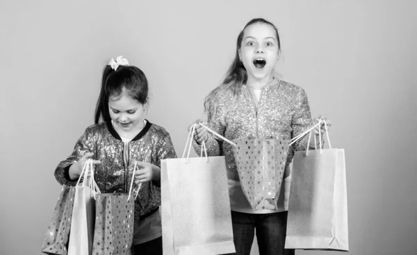 Esperar mais. Paga menos. Meninas irmãs amigos com sacos de compras fundo bege. Compras e compras. Sexta-feira negra. Venda e desconto. Dia das compras. As crianças têm muitos pacotes. Crianças moda — Fotografia de Stock