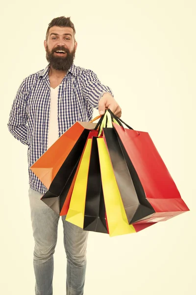 Las bolsas están llenas. Comprador hipster feliz sosteniendo bolsas aisladas en blanco. Hombre barbudo sonriendo con bolsas de papel después de la venta estacional. Llevar compras navideñas en bolsas de colores —  Fotos de Stock